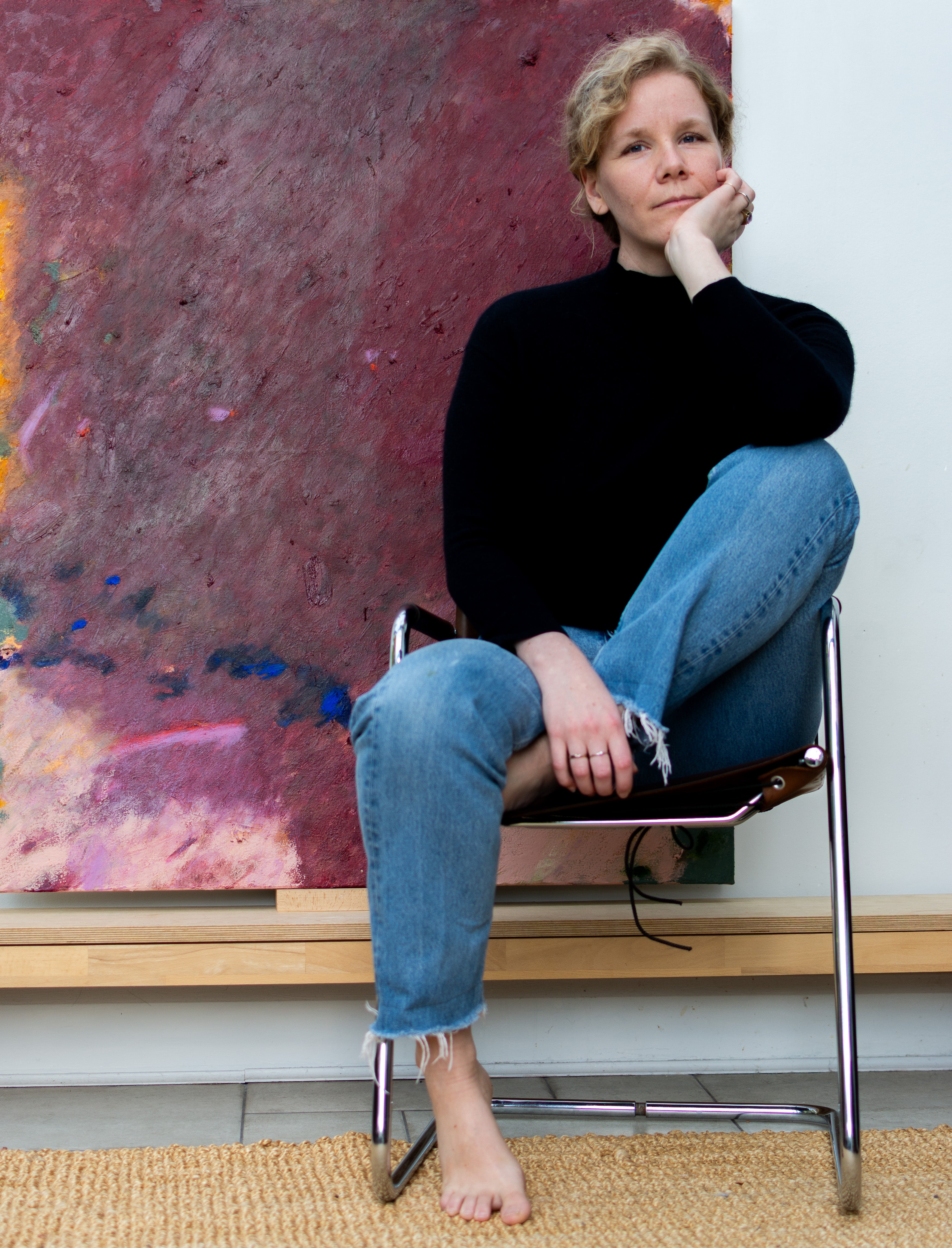 Abstract Painter Carolin Meier in front of her large scale maroon and bordeaux, expressive painting on canvas in her South London Art Studio